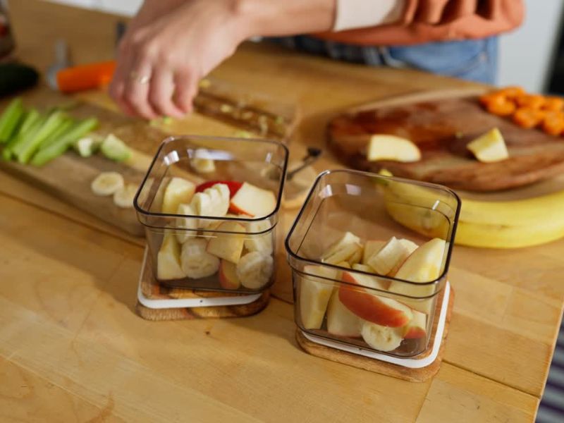 osoba pakuje isečeno voće u staklene činije